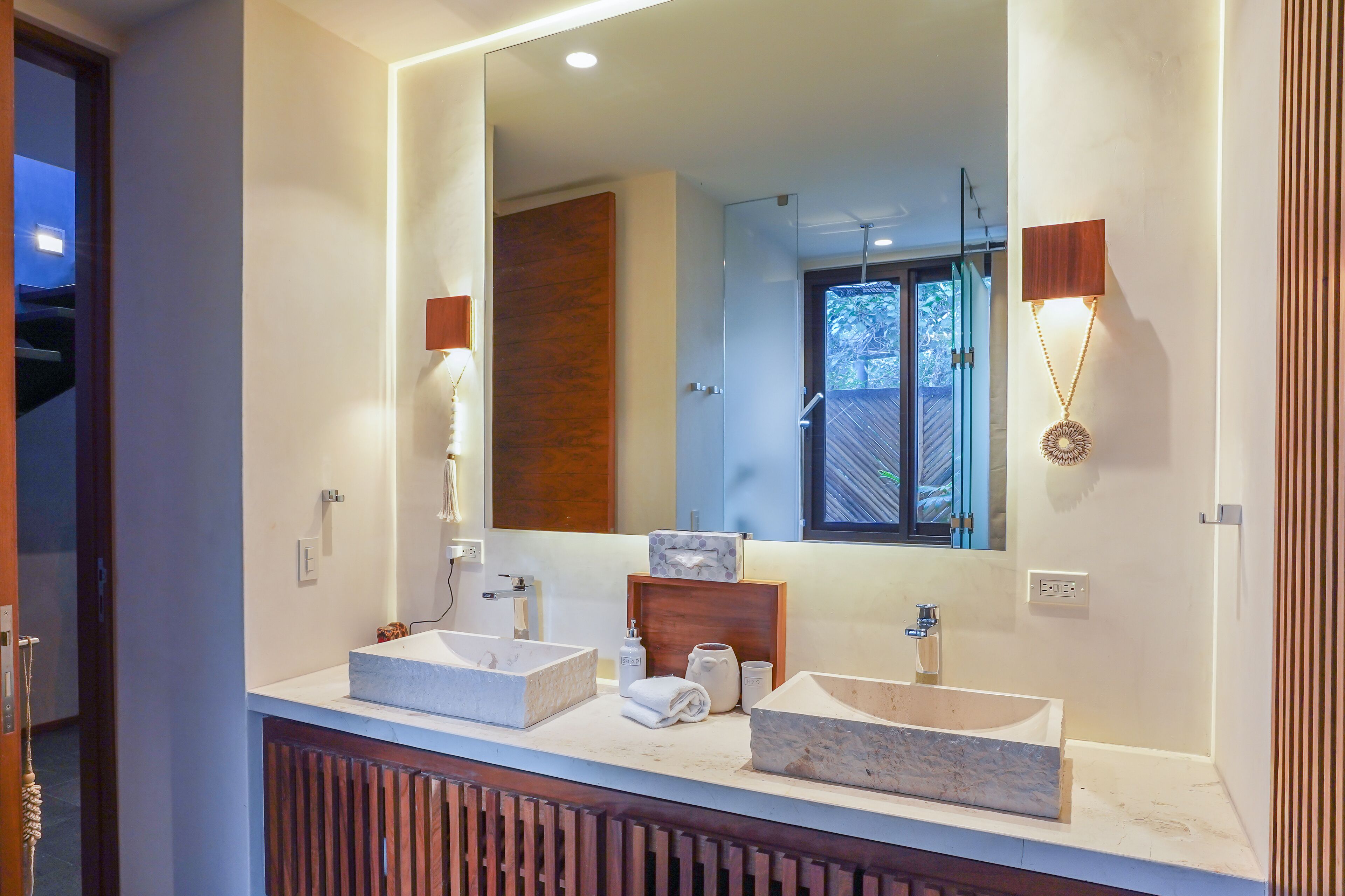 Une salle de bain moderne avec deux vasques, un grand miroir et un meuble-lavabo en bois.