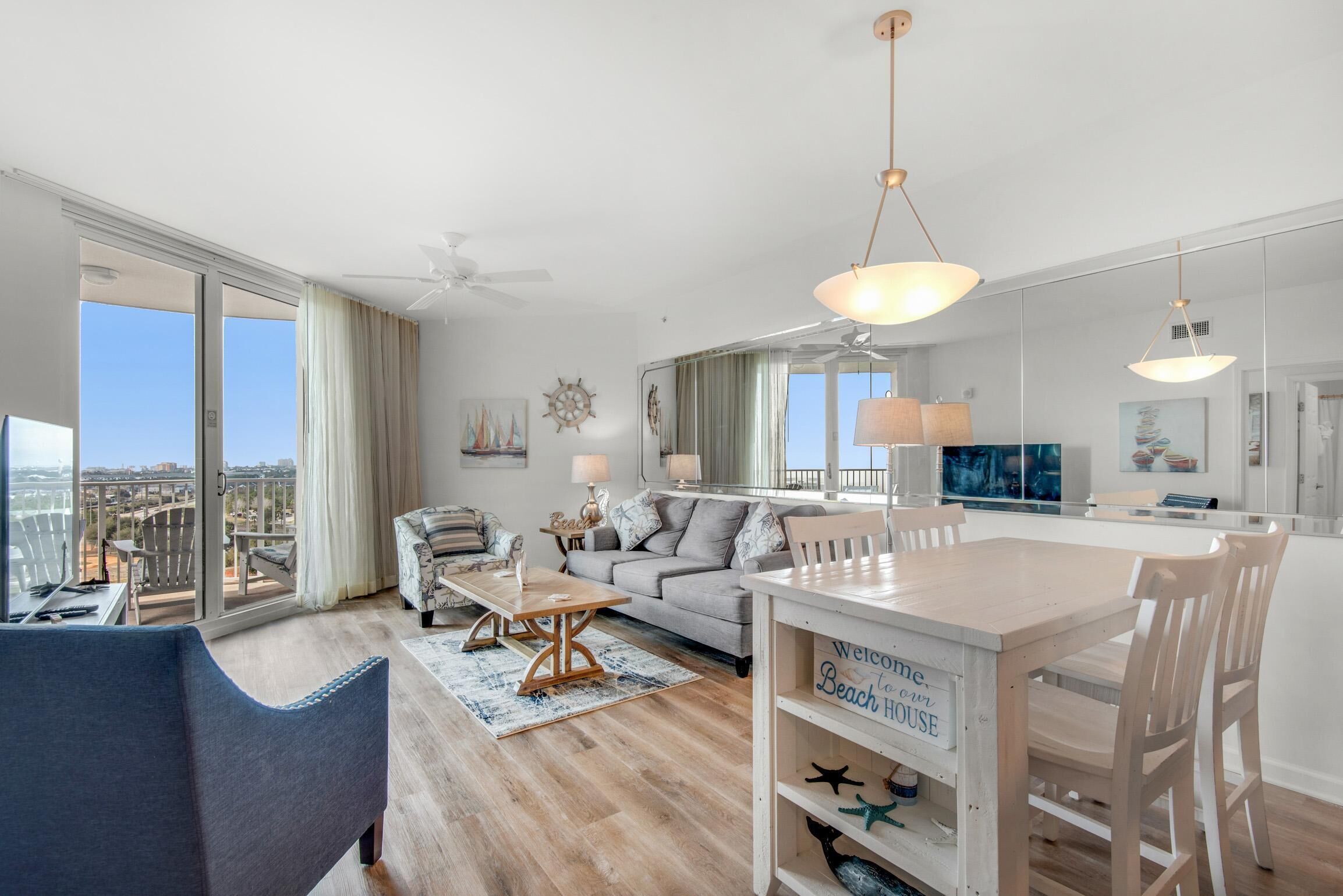 A spacious living area with a large window, a ceiling fan, and a dining table with chairs.
