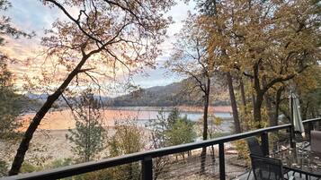 A scenic view from a balcony overlooking a lake with trees and distant hills.
