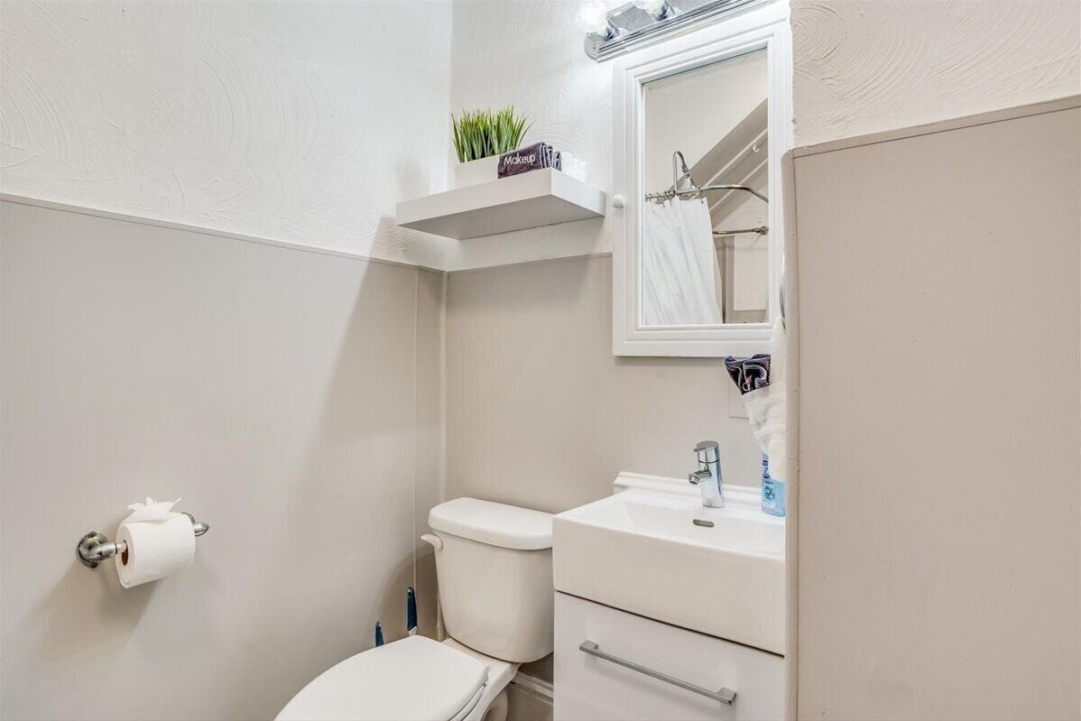 A small bathroom with a toilet, sink, and mirror.