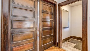 A wooden door with a panel design, leading to a room with a white wall and a small rug on the floor. - Travel Nurse Landing in Delano! W&D In Unit (Wichita)