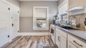 A kitchen with a window, white cabinets, a stove, and a sink. - Travel Nurse Landing in Delano! W&D In Unit (Wichita)