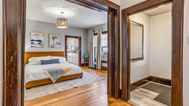 A bedroom with a wooden bed, a ceiling light, and artwork on the wall. - Travel Nurse Landing in Delano! W&D In Unit (Wichita)