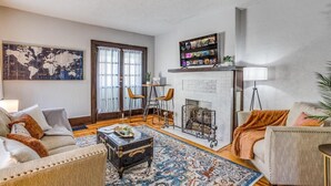 A living room with a fireplace, a world map artwork, a bookshelf, and a coffee table. - Travel Nurse Landing in Delano! W&D In Unit (Wichita)
