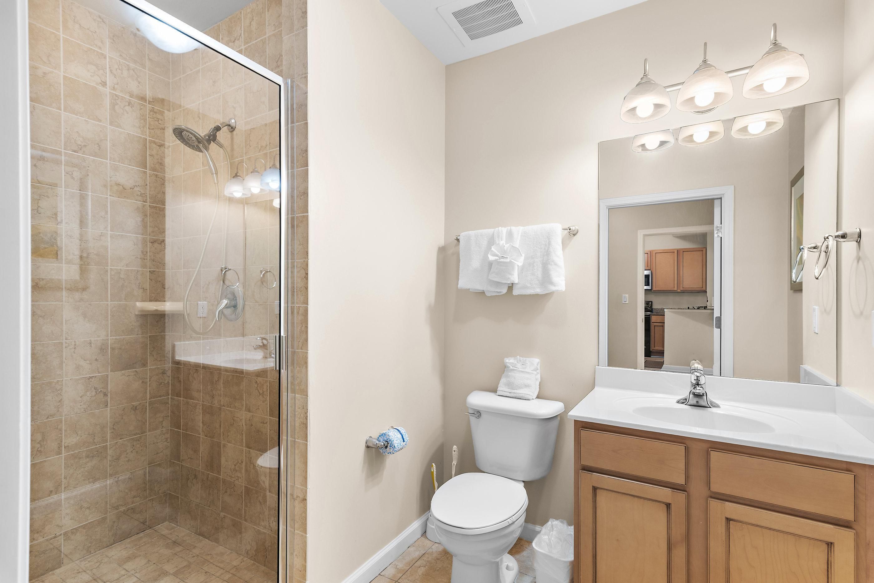 A modern bathroom with a glass-enclosed shower, a toilet, a sink, and a vanity with a mirror.
