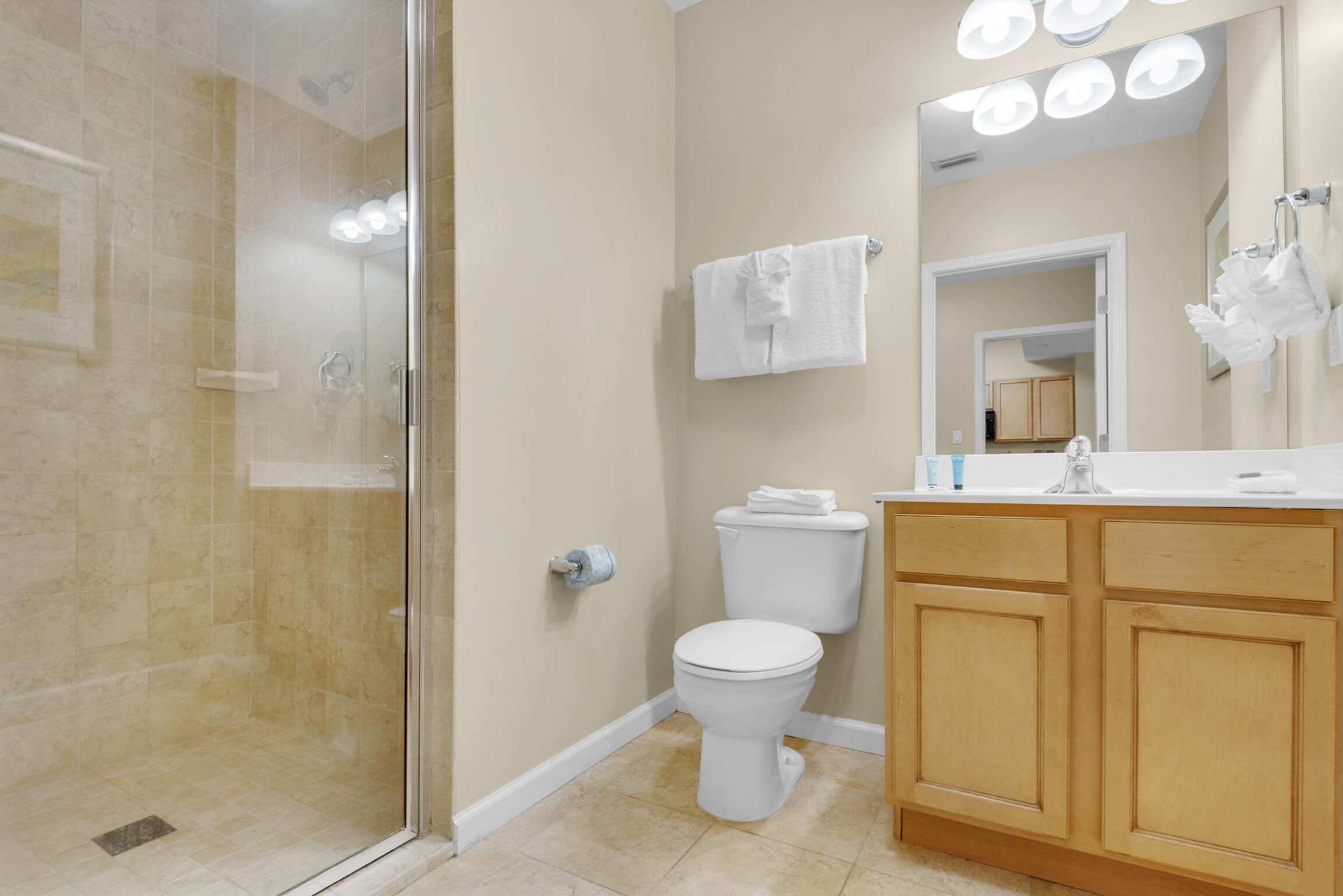A bathroom with a glass shower enclosure, a toilet, a sink with a mirror, and a towel rack.