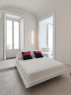 A modern bedroom with a bed, two pillows, a bedside table, and a large mirror. - Casa Celeste Aida  (Naples)