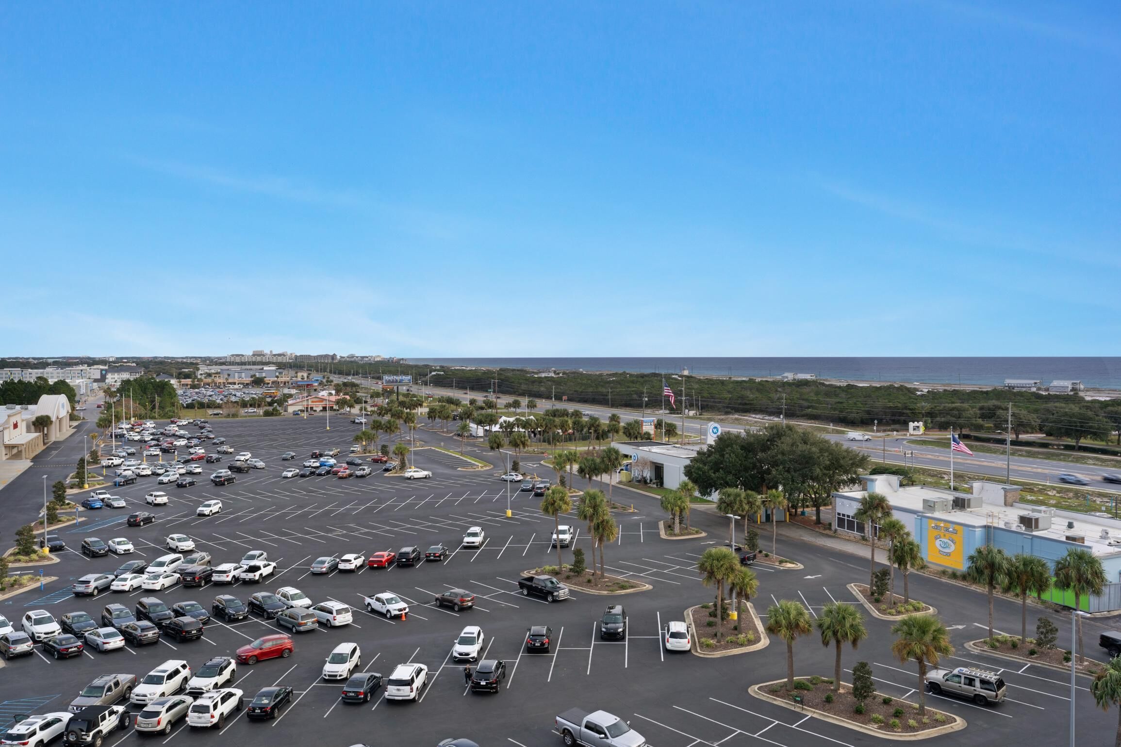 Un parking rempli de voitures, un bâtiment avec un toit bleu et un ciel dégagé.