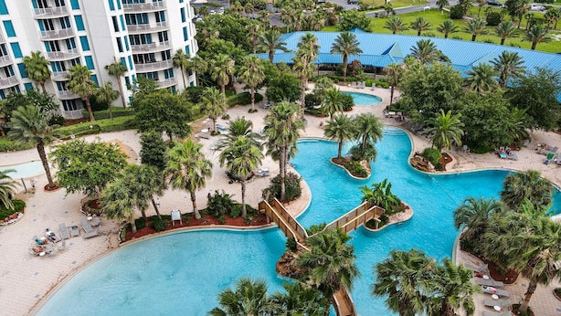 A resort with multiple swimming pools surrounded by palm trees and lounge areas. - Palms Resort #1813 Jr. 2BR (Destin)