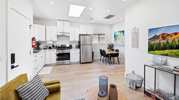 A modern kitchen with white cabinets, stainless steel appliances, and a dining area with a table and chairs. - Cozy Prvate ADU close to Disney Beach EV (Garden Grove)