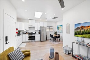 A modern kitchen with white cabinets, stainless steel appliances, and a dining area with a table and chairs. - Cozy Prvate ADU close to Disney Beach EV (Garden Grove)