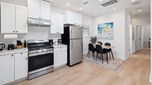 A modern kitchen with white cabinets, stainless steel appliances, and a dining area with a table and chairs. - Cozy Prvate ADU close to Disney Beach EV (Garden Grove)