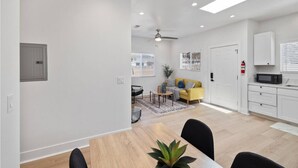 A modern living room with a sofa, coffee table, and a dining area with a table and chairs. - Cozy Prvate ADU close to Disney Beach EV (Garden Grove)