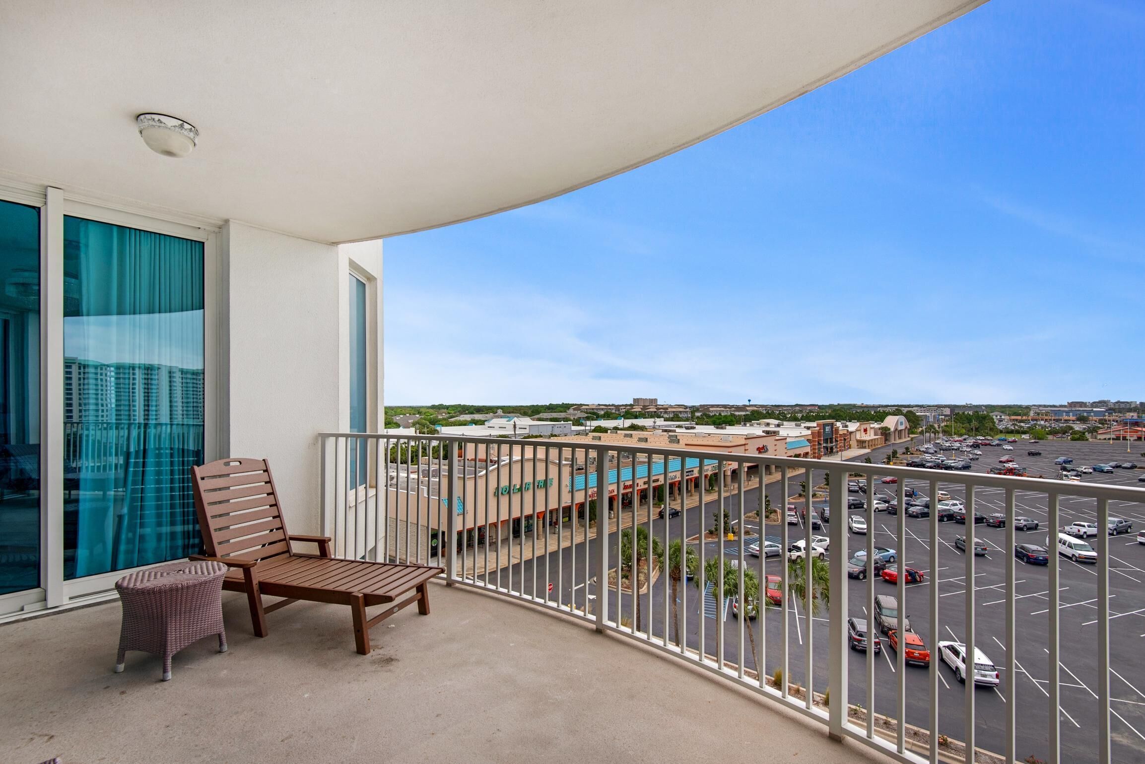 A balcony with a view of a parking lot and buildings.