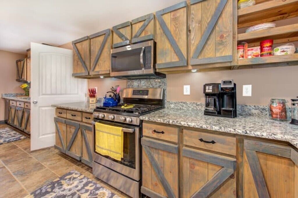 A kitchen with wooden cabinetry, a stove, a microwave, and a coffee maker.