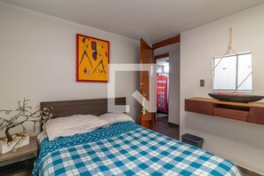 Relax in a cozy retreat with a checkered bedspread, a wooden headboard, and a beautiful view.