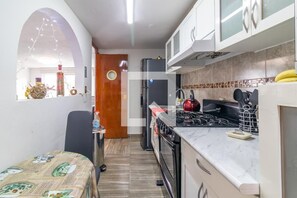 Compact kitchen with gas stove, refrigerator, and sink, featuring a dining area with a table.