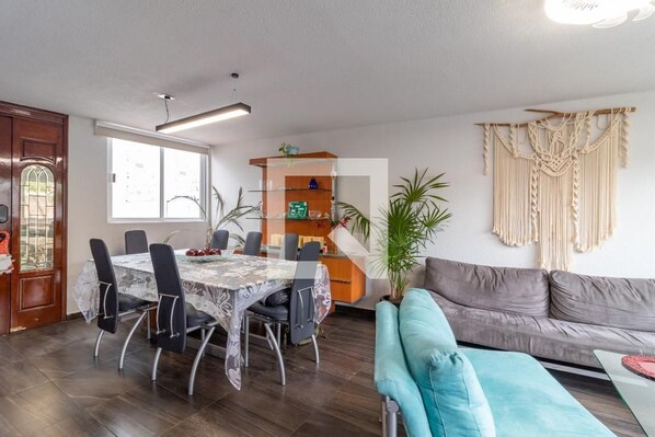 Relax in this stylish living space with a dining area, sofa, and macrame wall hanging.