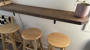 A kitchen area with a wooden countertop, three wooden stools, and a potted plant. - The Tiny House Experience, at that Treasure House .. 2 bed loft & 1 bath (Smyrna)