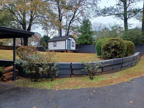Situated in a tranquil setting, this house features a small, single-story design with a yard and a wooden fence.