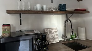 A kitchen with a microwave, coffee maker, and a sign with positive messages. - The Tiny House Experience, at that Treasure House .. 2 bed loft & 1 bath (Smyrna)