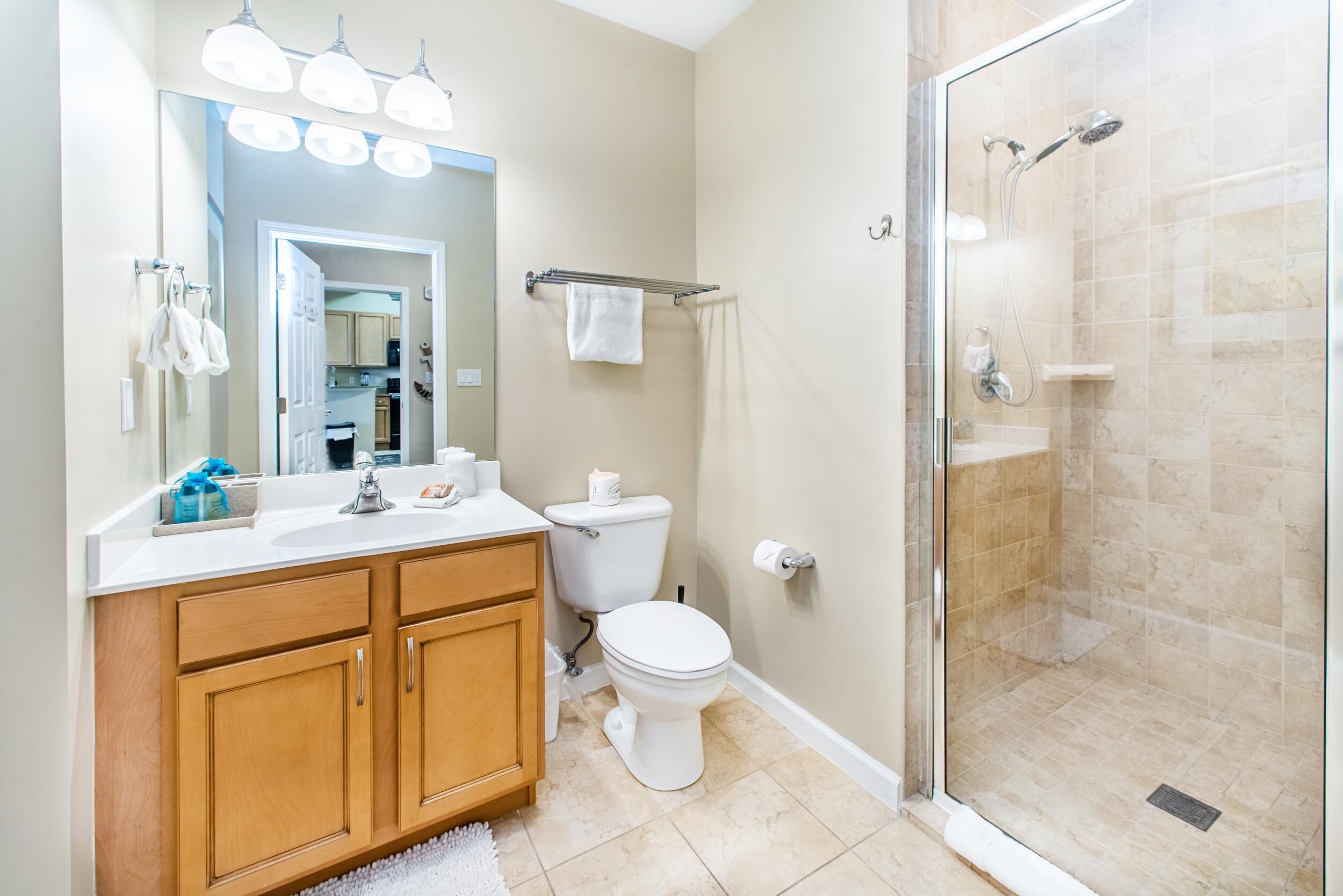 A bathroom with a shower, toilet, sink, and wooden cabinets.