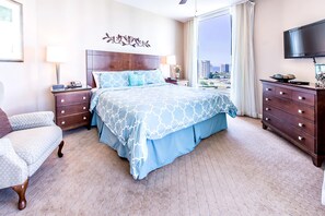 A hotel room with a large bed, two bedside tables, a chair, a dresser, and a TV.