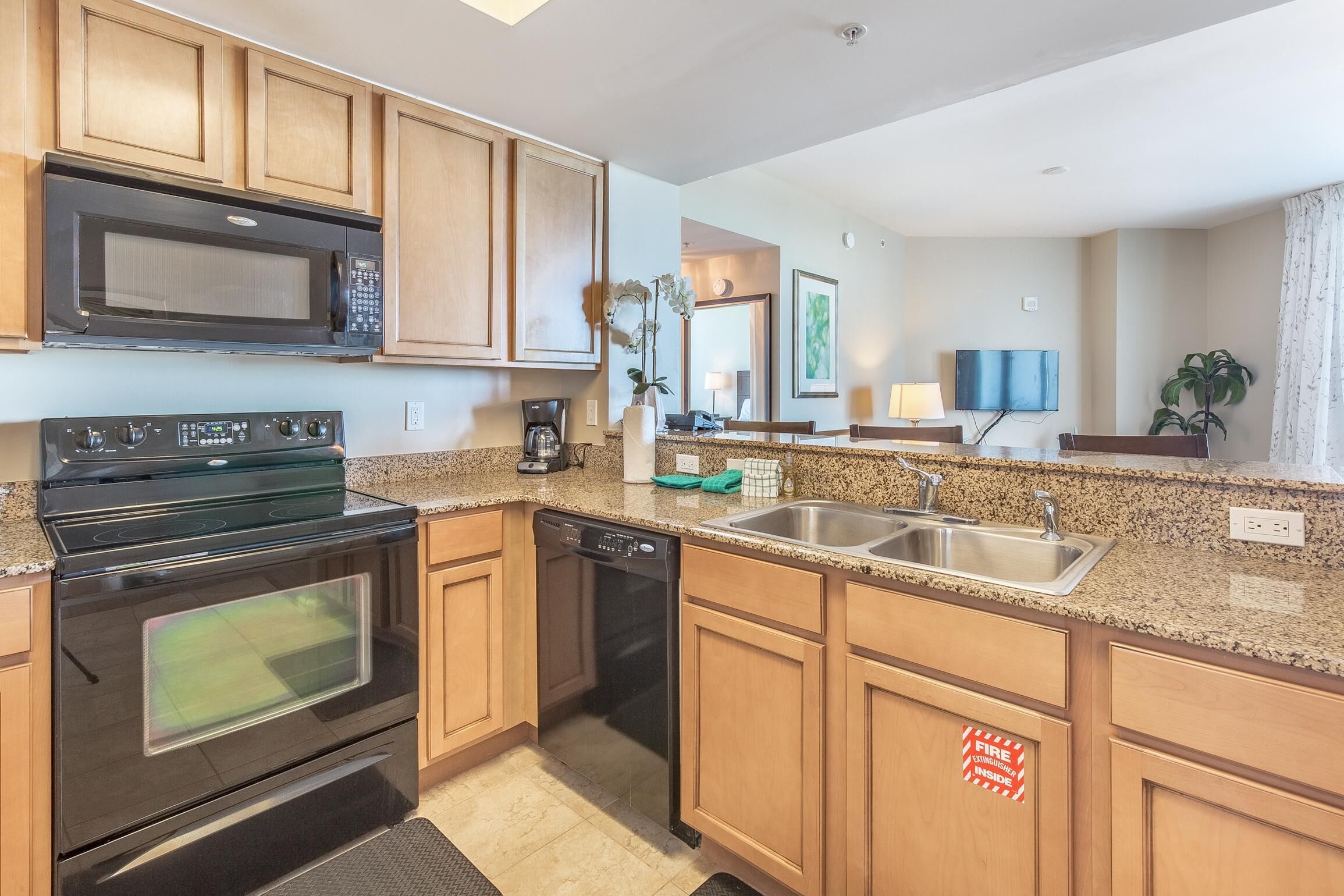 A modern kitchen with wooden cabinets, a stainless steel sink, a microwave, an oven, and a dishwasher.
