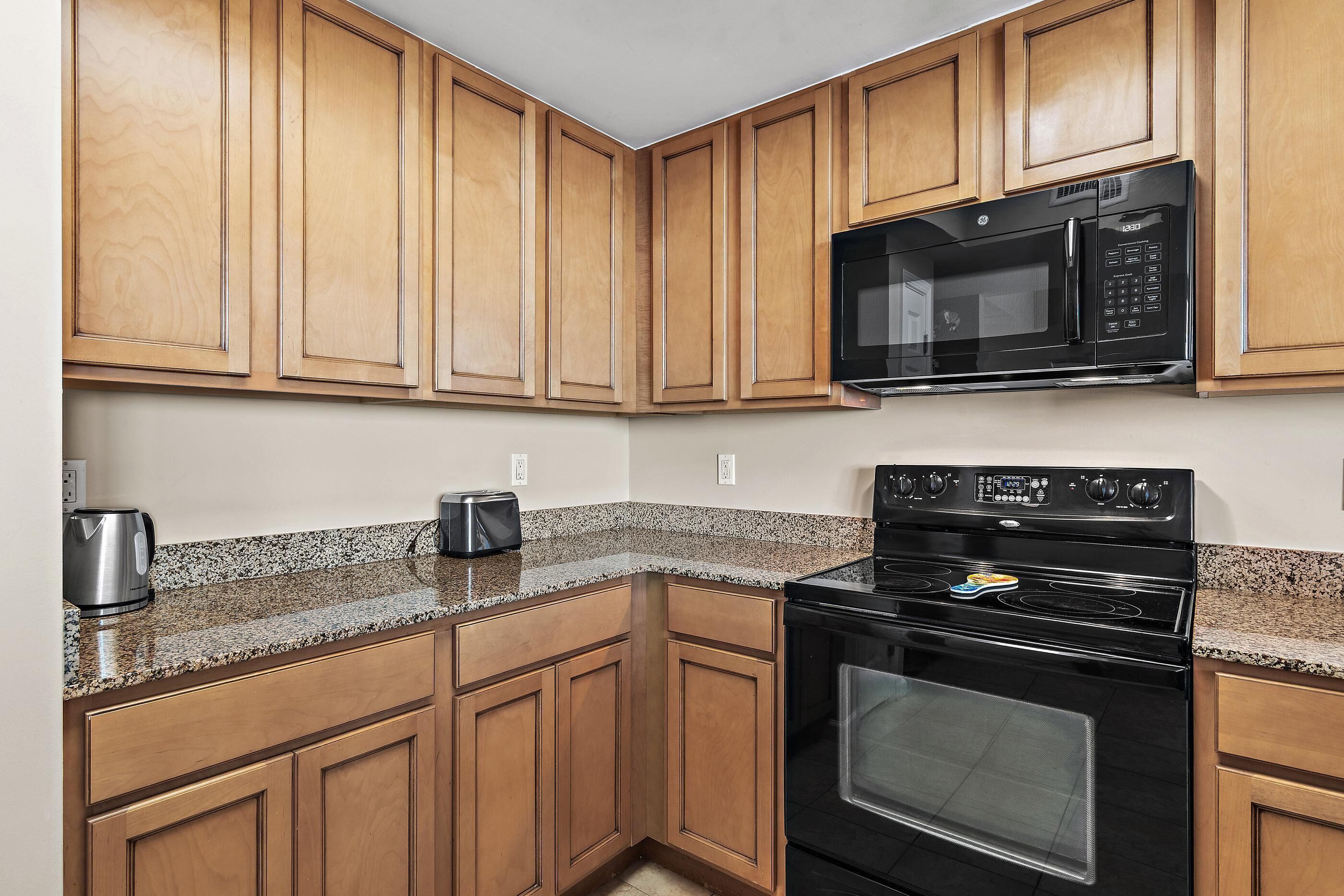 A kitchen with wooden cabinets, a black microwave, and a stove.