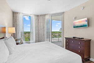 Habitación de hotel con una cama grande, una cómoda, un cuadro y vistas al exterior.