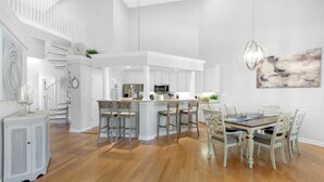 A spacious kitchen with a central island, white cabinetry, and a dining area with a wooden table and chairs. - Thirsty Turtle (Miramar Beach)