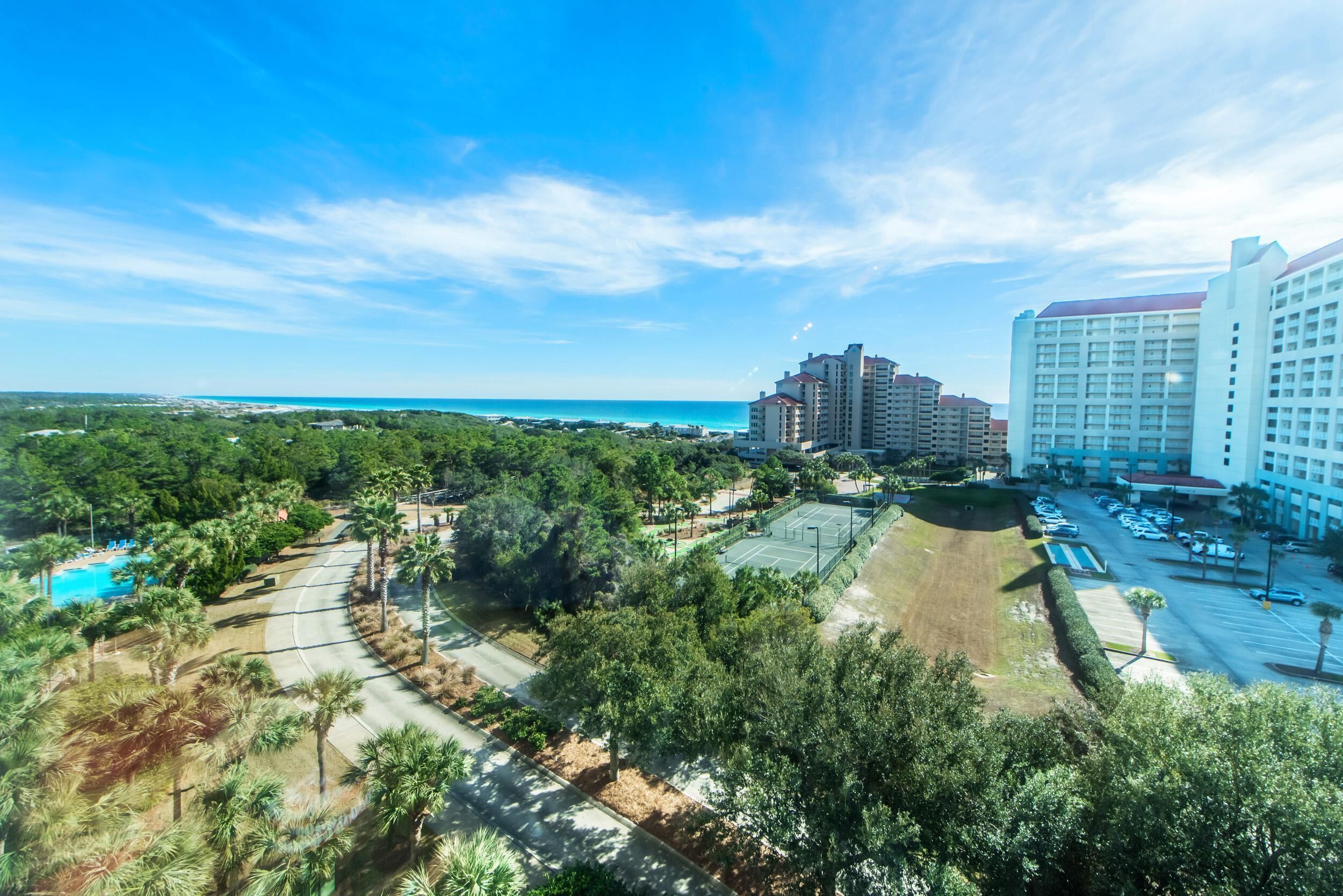 A resort with a tennis court, pool, and beachfront view.