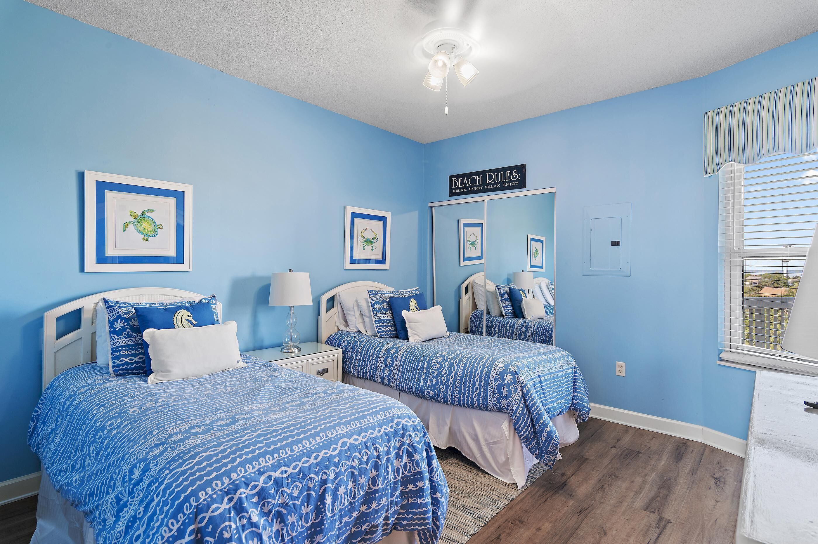 A room with two beds, a mirror, and a sign reading "Beach Rules."