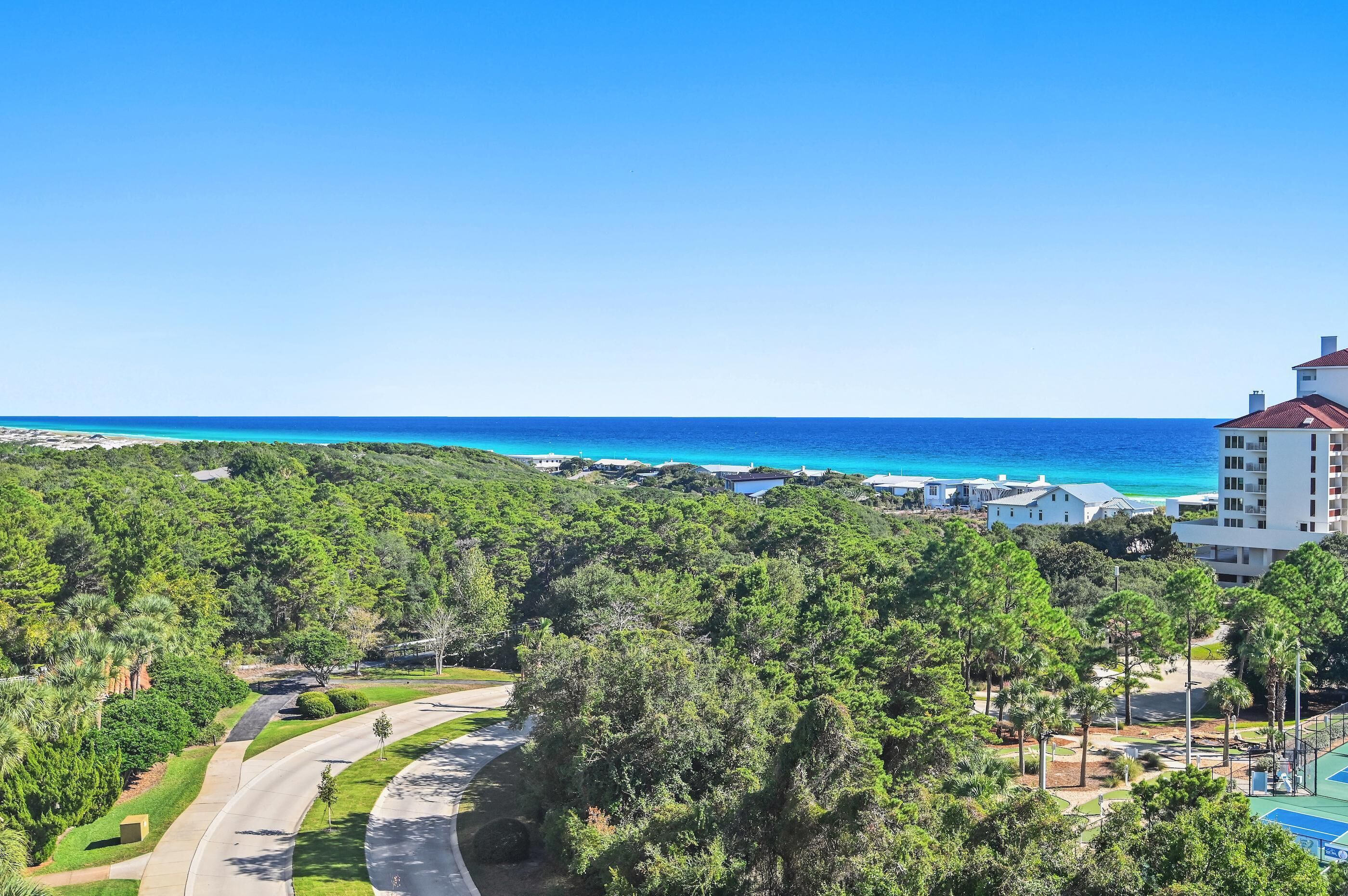 Un resort costero con una carretera sinuosa, vegetación exuberante y vistas al océano.