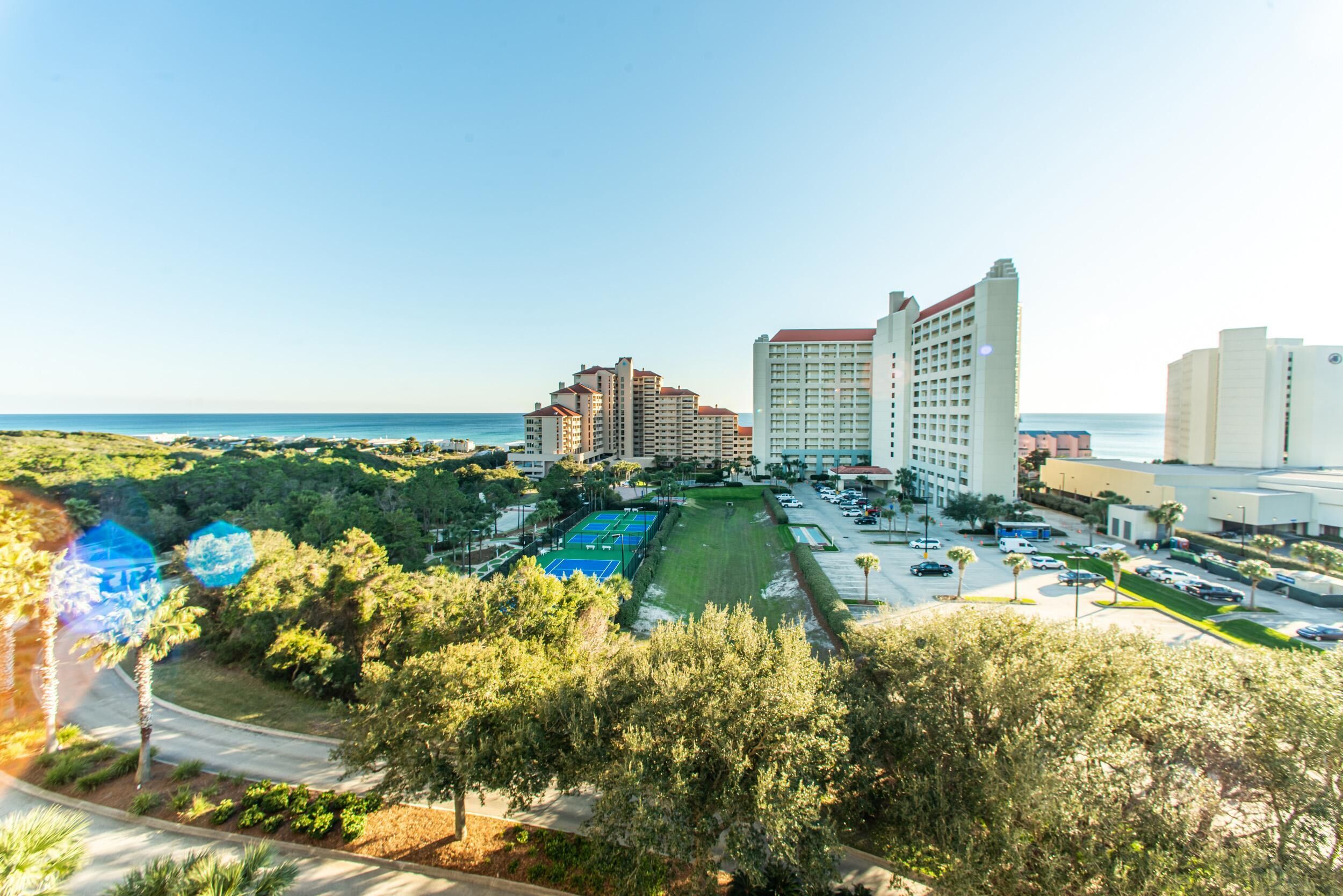 A hotel with multiple high-rise buildings, a parking lot, and a view of the ocean.