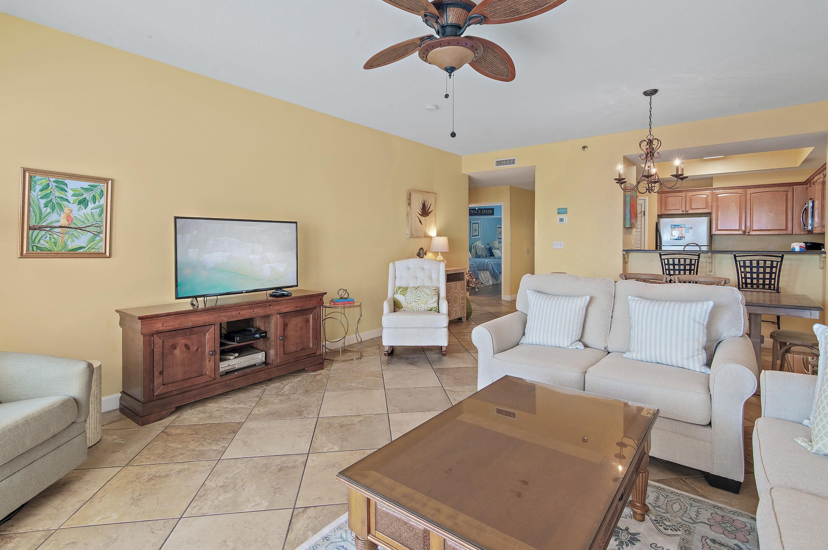 A living room with a television, a white armchair, a beige sofa, and a coffee table.