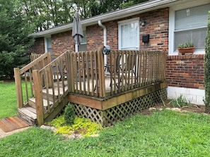 A residential house with a wooden deck, a brick exterior, and a small garden area with yellow flowers.