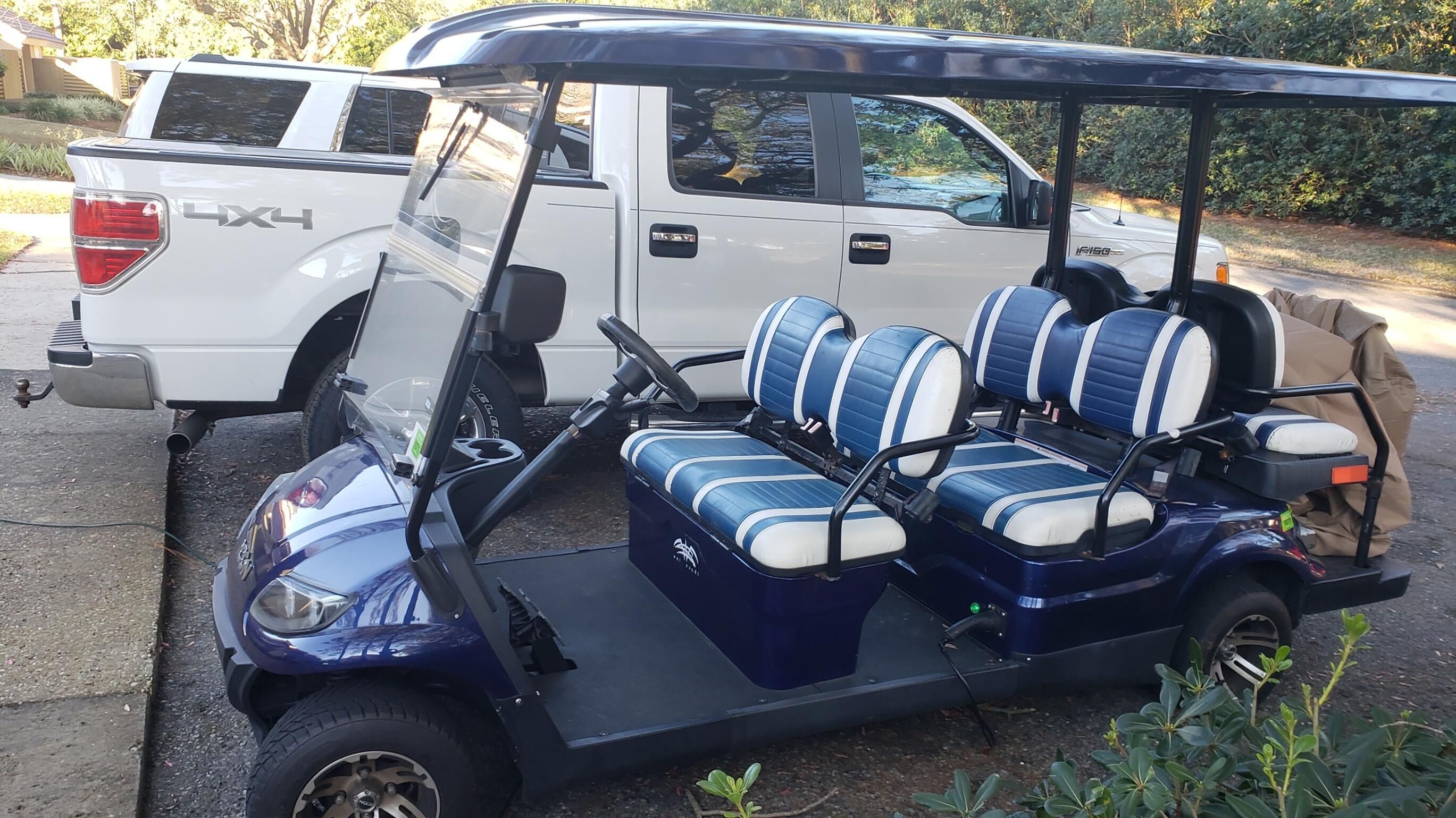 A golf cart with blue and white seats, a steering wheel, and a black canopy.