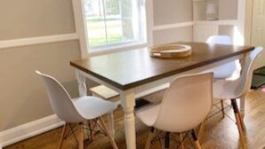 A dining area with a wooden table and four white chairs. - Hangout House play, work, and visit (Nashville)