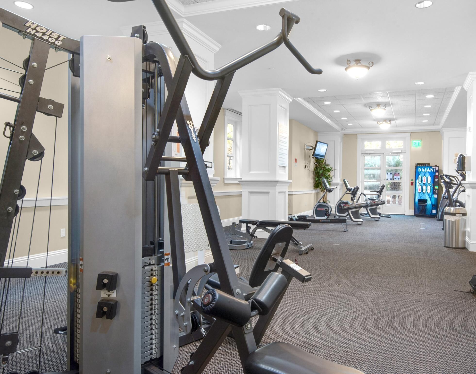A gym with various exercise equipment, including a cable machine and treadmills.