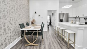 A modern kitchen with white cabinets, a stainless steel refrigerator, and a bar area with stools. - NEW,Vibrant, 4BR house, centrally located, photo wall, Gated  (Houston)