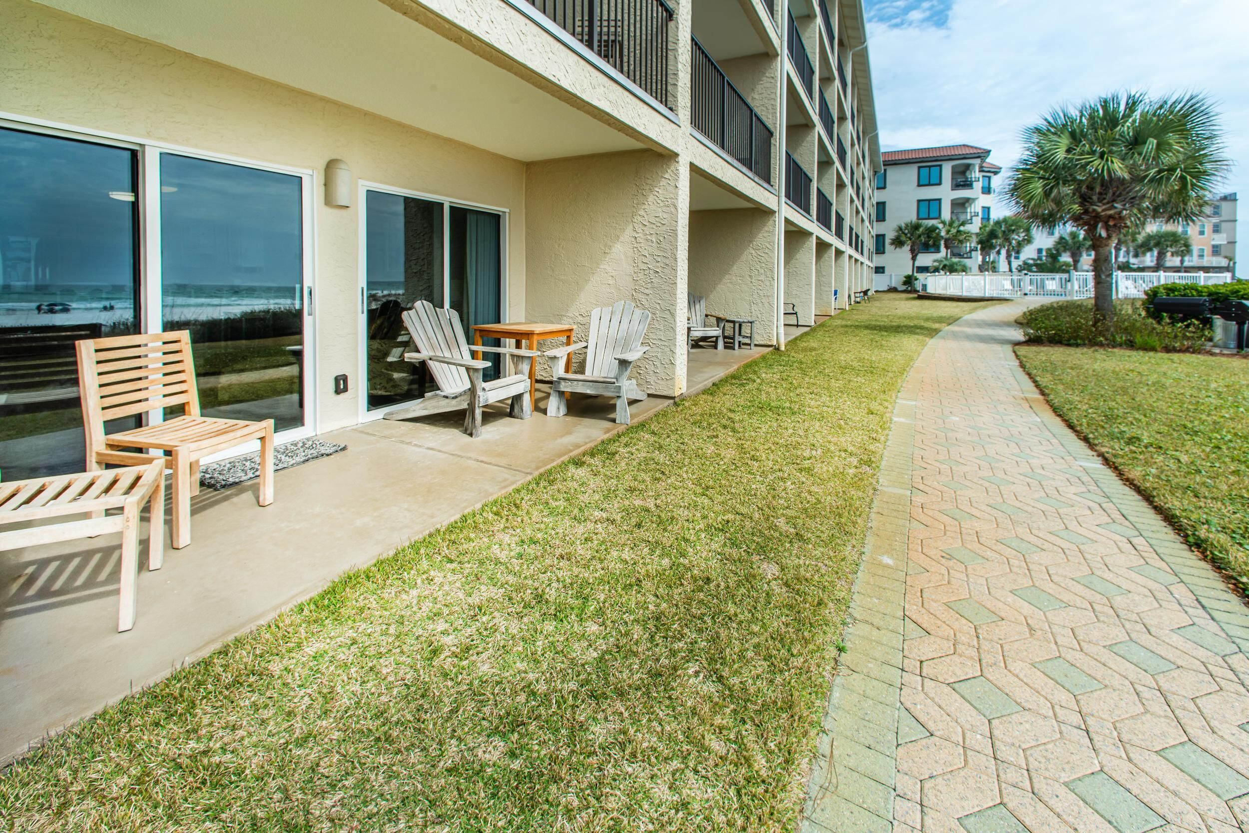 A hotel with a patio area featuring outdoor furniture, a pathway, and a view of the ocean.