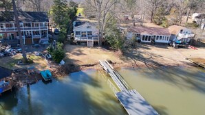 A lakeside property with a dock, a boat, and a house with a porch. - Lure & Leisure Lakehouse | Lake Murray 3BR 2BA (Prosperity)