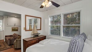 A bedroom with a bed, a dresser, a sailboat model, a ceiling fan, and a window with blinds. - Lure & Leisure Lakehouse | Lake Murray 3BR 2BA (Prosperity)
