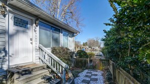 A house with a front porch, a staircase, and a small garden area with a wooden fence and greenery. - Lure & Leisure Lakehouse | Lake Murray 3BR 2BA (Prosperity)
