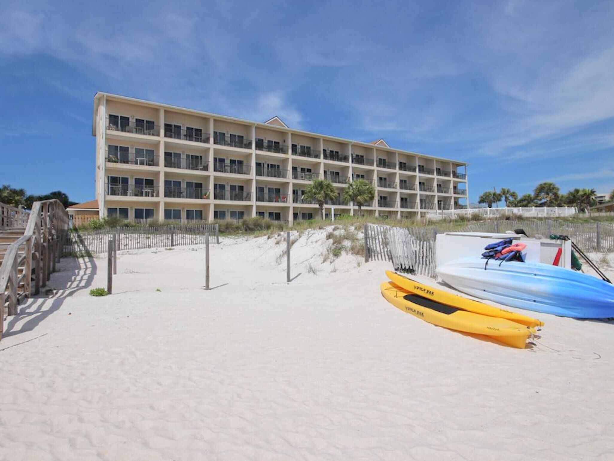 A beachfront hotel with multiple balconies and a sandy beach area.