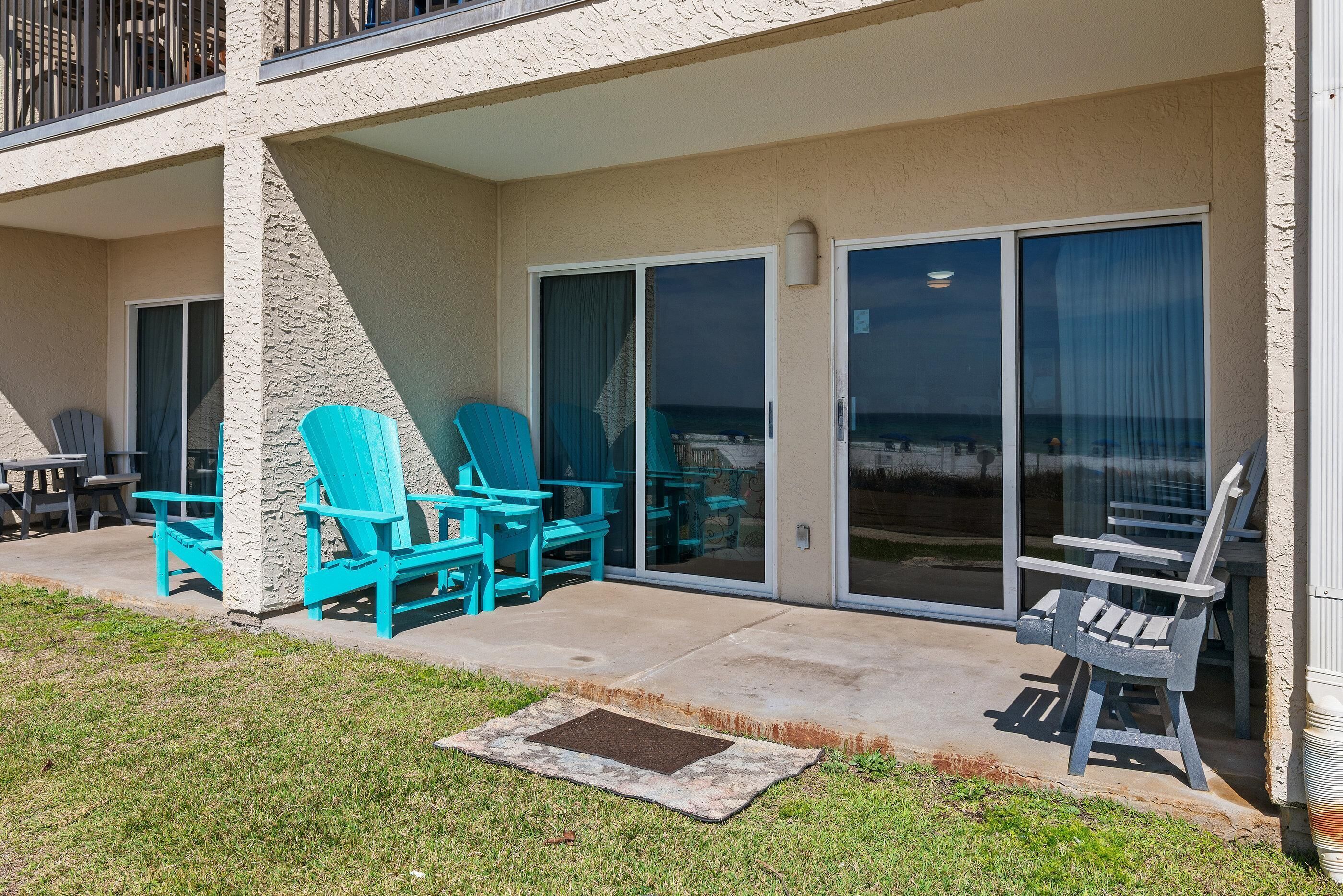 A covered outdoor area with turquoise chairs and a concrete patio.