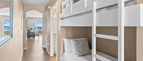 A bunk bed room with a view of the beach, a dining area, and a bathroom.