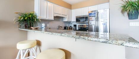 A modern kitchen with white cabinets, stainless steel appliances, and a granite countertop.