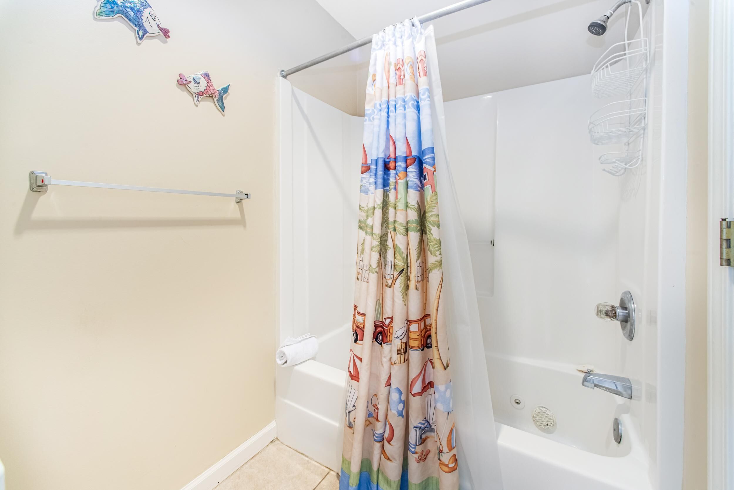 A bathroom with a shower curtain featuring a tropical print, a white bathtub, and a towel rack.
